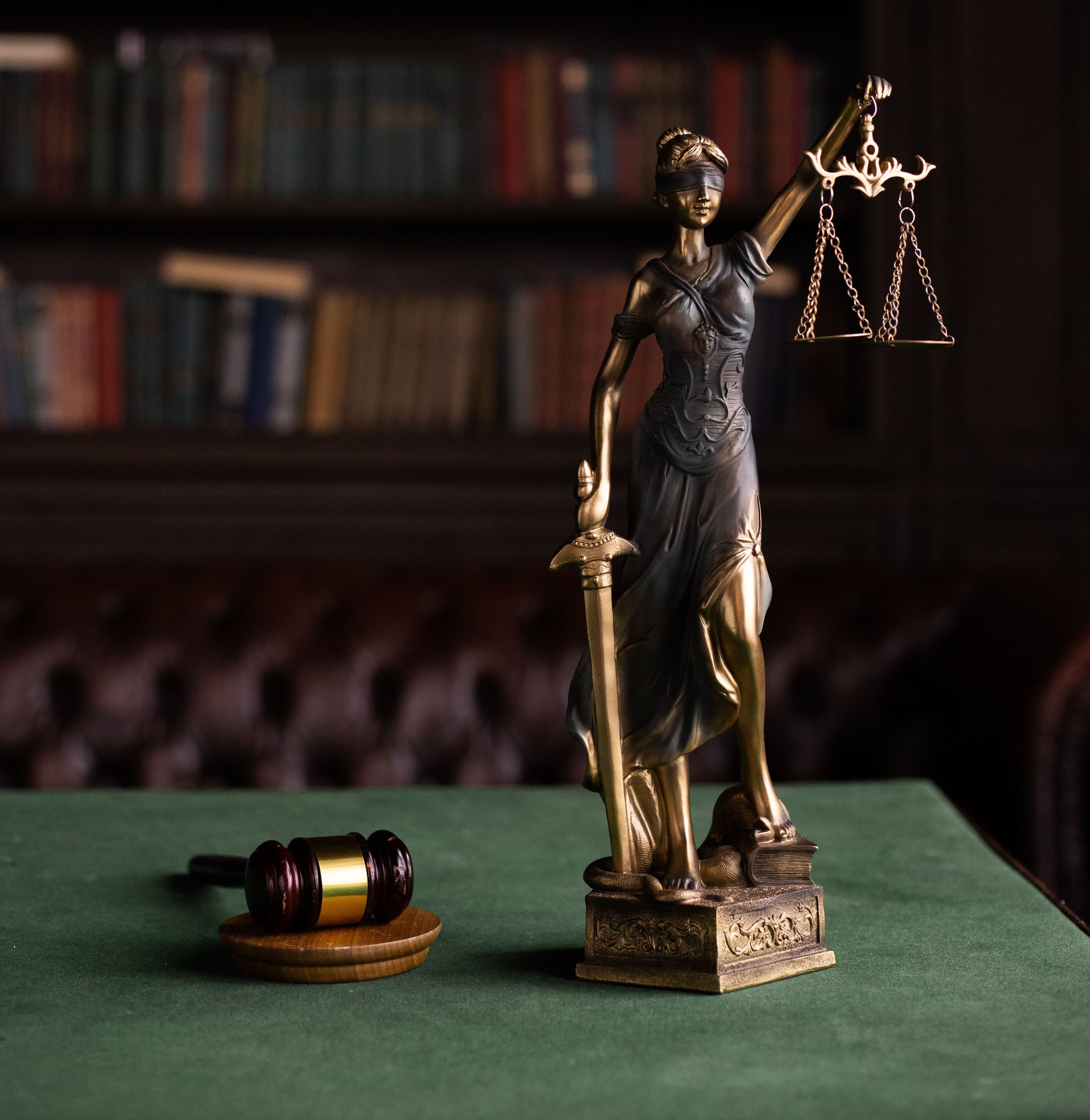 Eine Justitia-Figur neben juristischen Büchern
